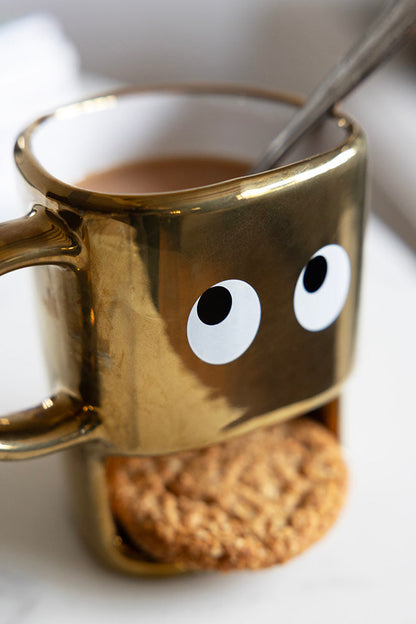 Tasse à biscuits dorés tenant un visage
